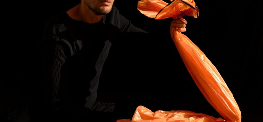 Bridges Festival artist Csaba Raduly holding an orange plastic bag puppet during the show Plastique presented during march break